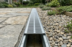 Drainage grate installed flush with a paved surface