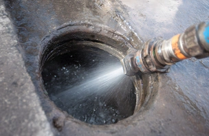 Hydro-jetting nozzle cleaning buildup from a drain line